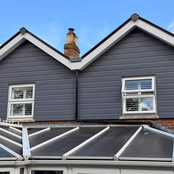 Twin gables with white bargeboards and fascias over grey cladding, above a conservatory