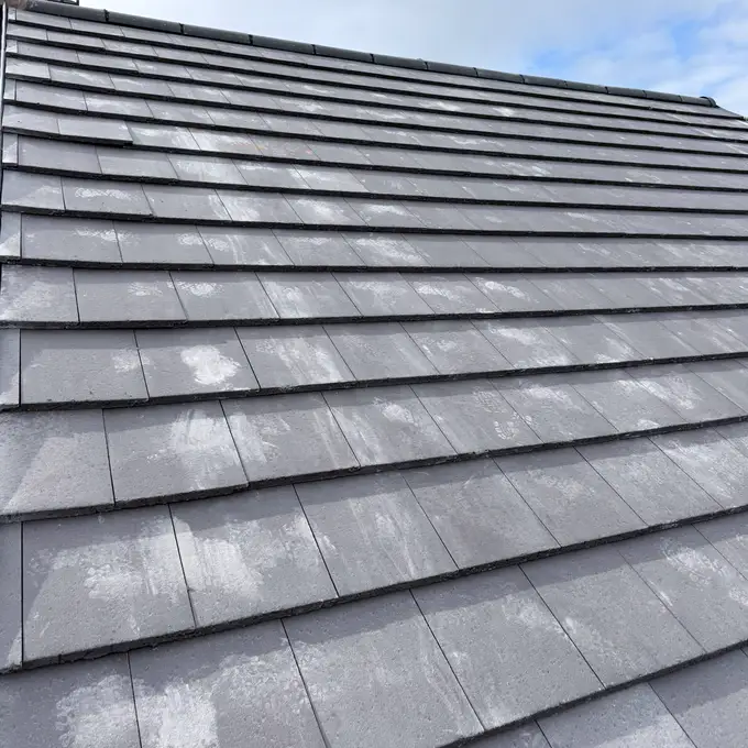 A newly laid grey tiled roof under a blue sky
