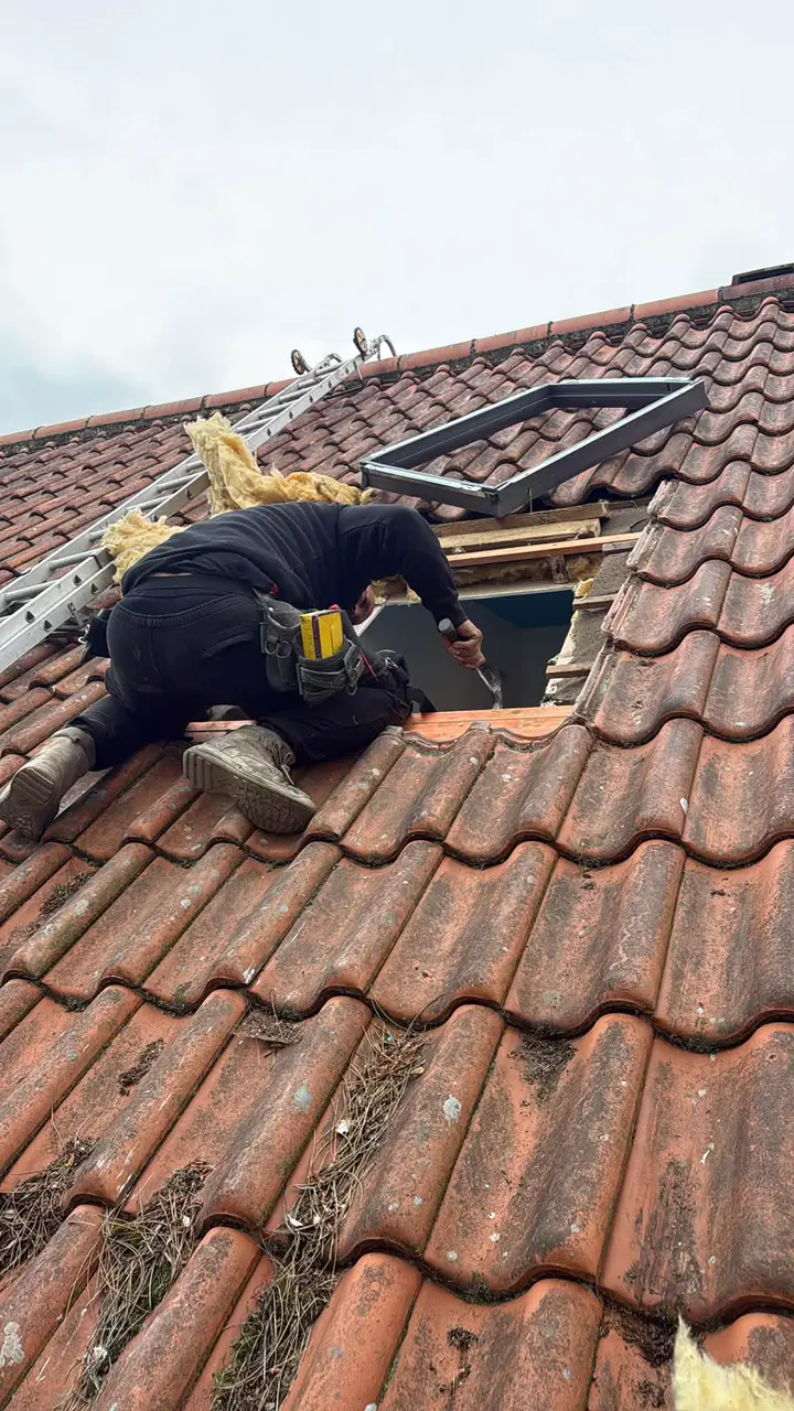 A roofer fitting a roof window into a clay tiled roof