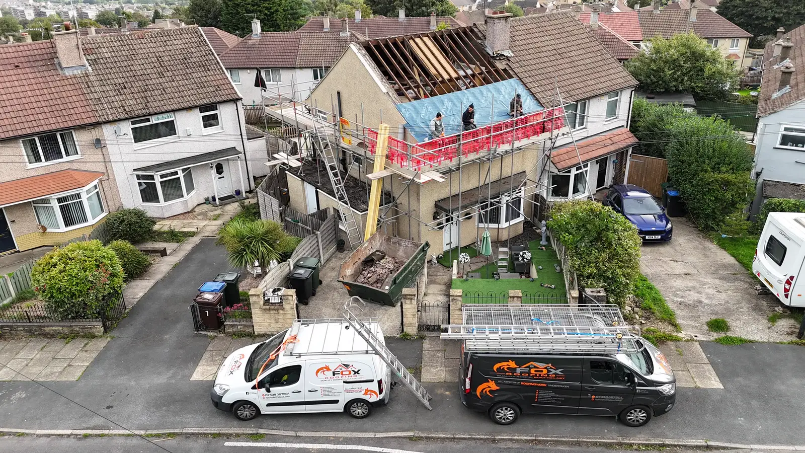 Aerial view of a semi-detached house stripped to the rafters for a re-roof, the team on the scaffold