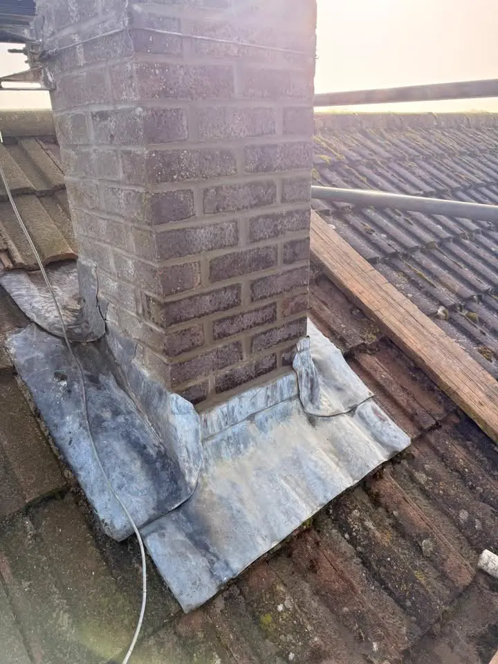 Before: old, weathered lead flashing around the base of a brick chimney stack
